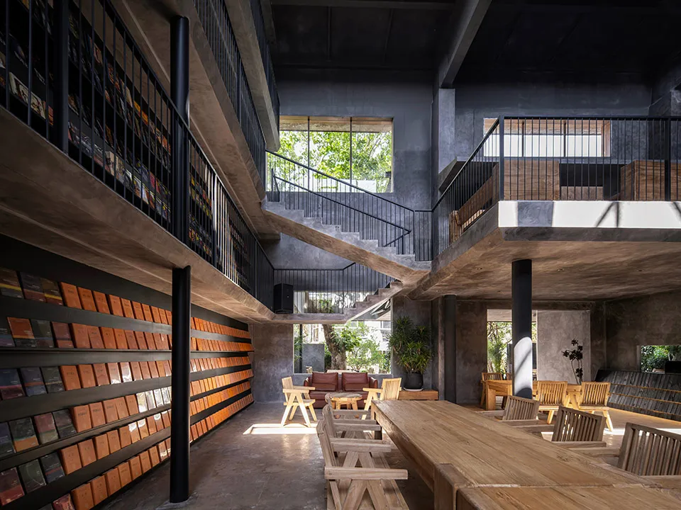 An industrial-style library with concrete walls and wooden furniture.