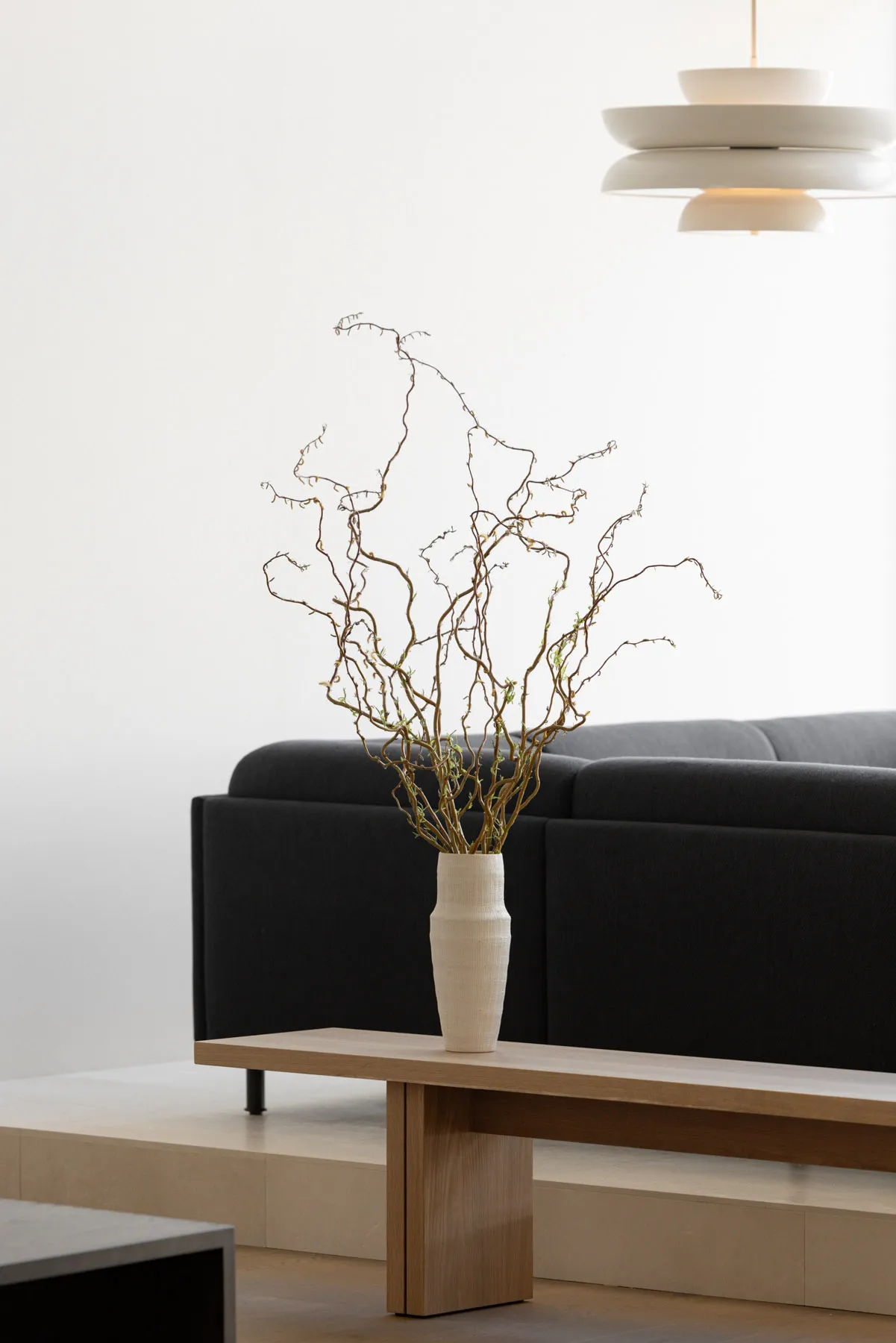 Modern living room featuring a low-profile sofa, wooden coffee table, concrete floor, and minimalist lighting fixtures.
