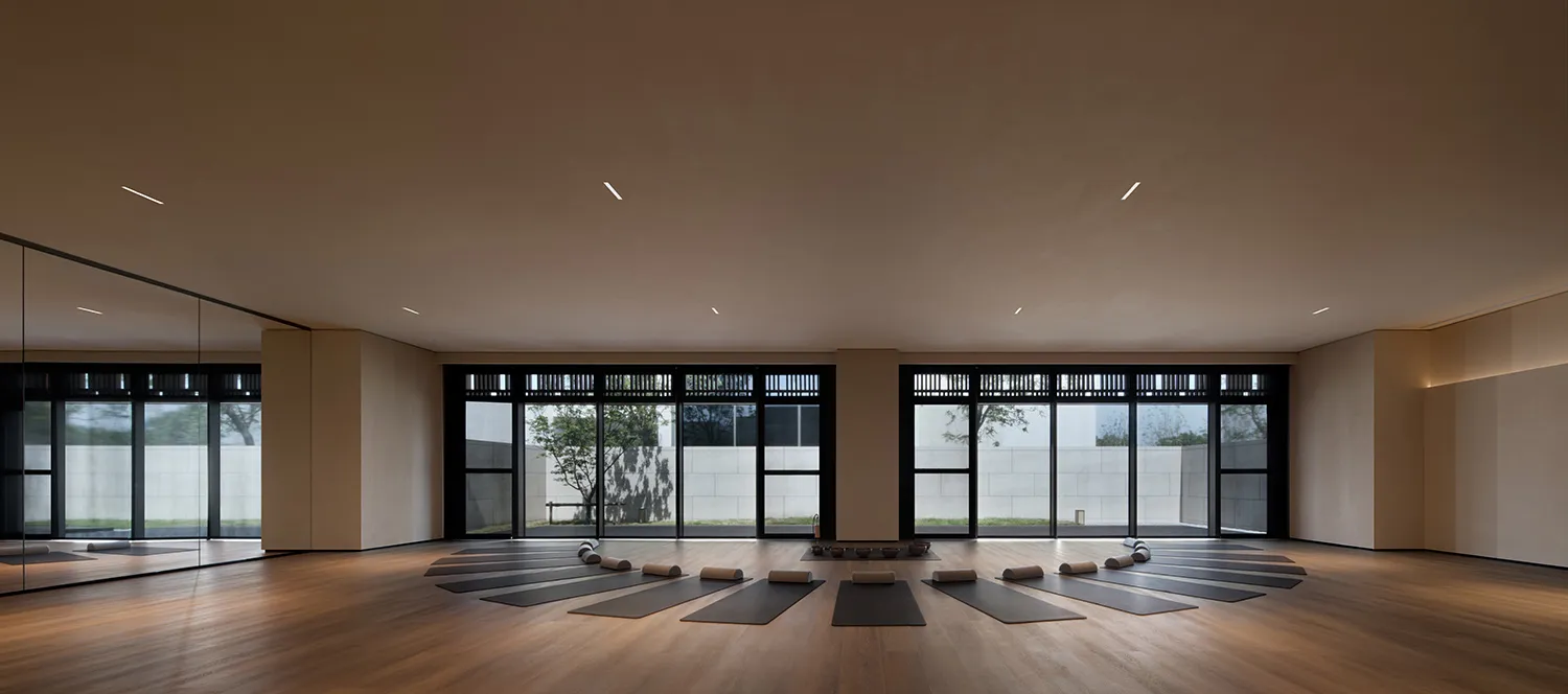 Yoga mats arranged in a circle on a hardwood floor in a minimalist yoga studio.