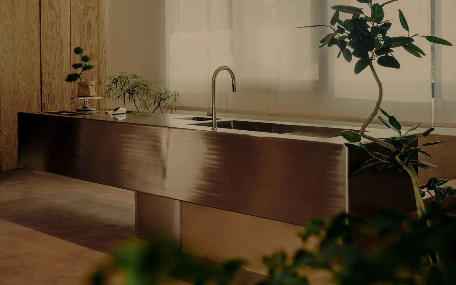 A contemporary kitchen interior features a sleek metal counter with a polished copper finish and a modern faucet.