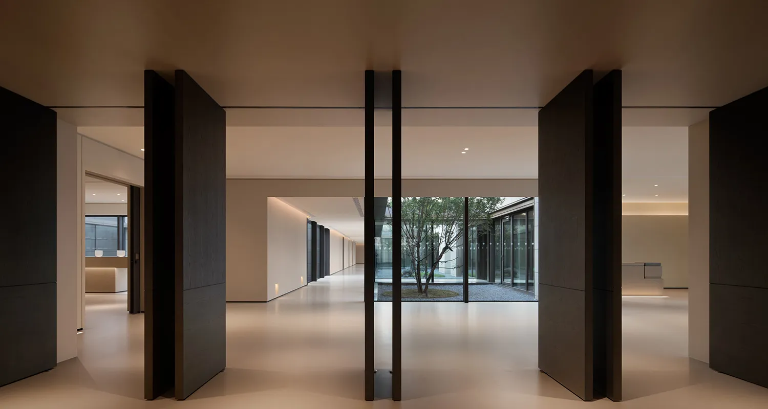 A modern office space featuring glass walls and wooden columns, creating a sleek and contemporary environment.