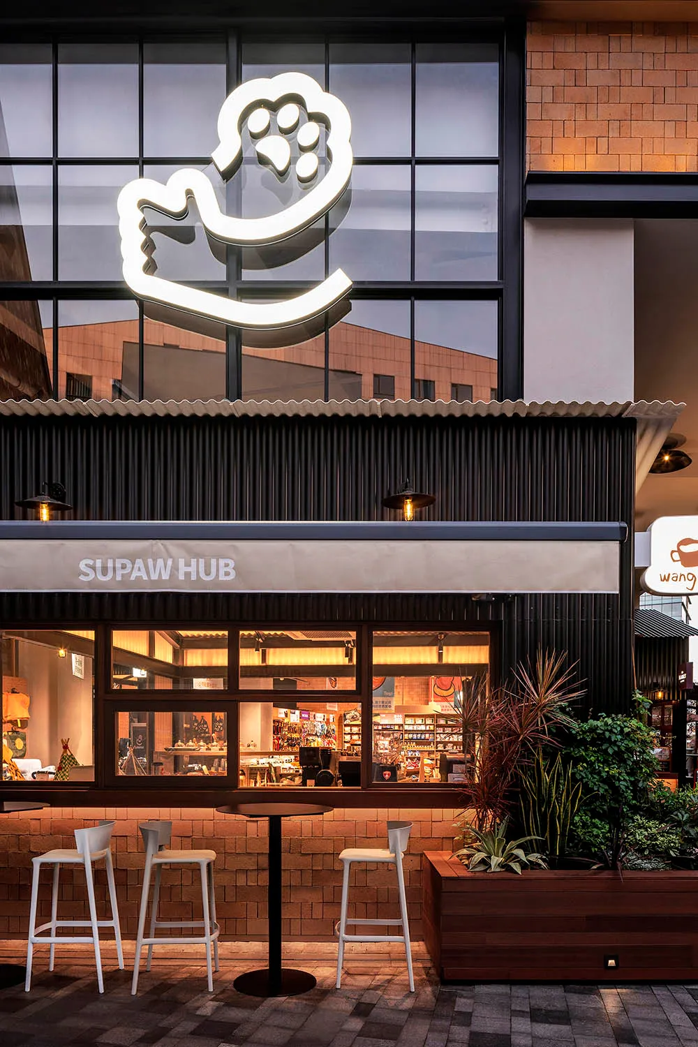 Modern retail storefront with brick and concrete materials and a paw print logo.