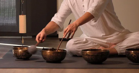 一位人士正使用木槌敲擊金屬缽，進行音樂治療。