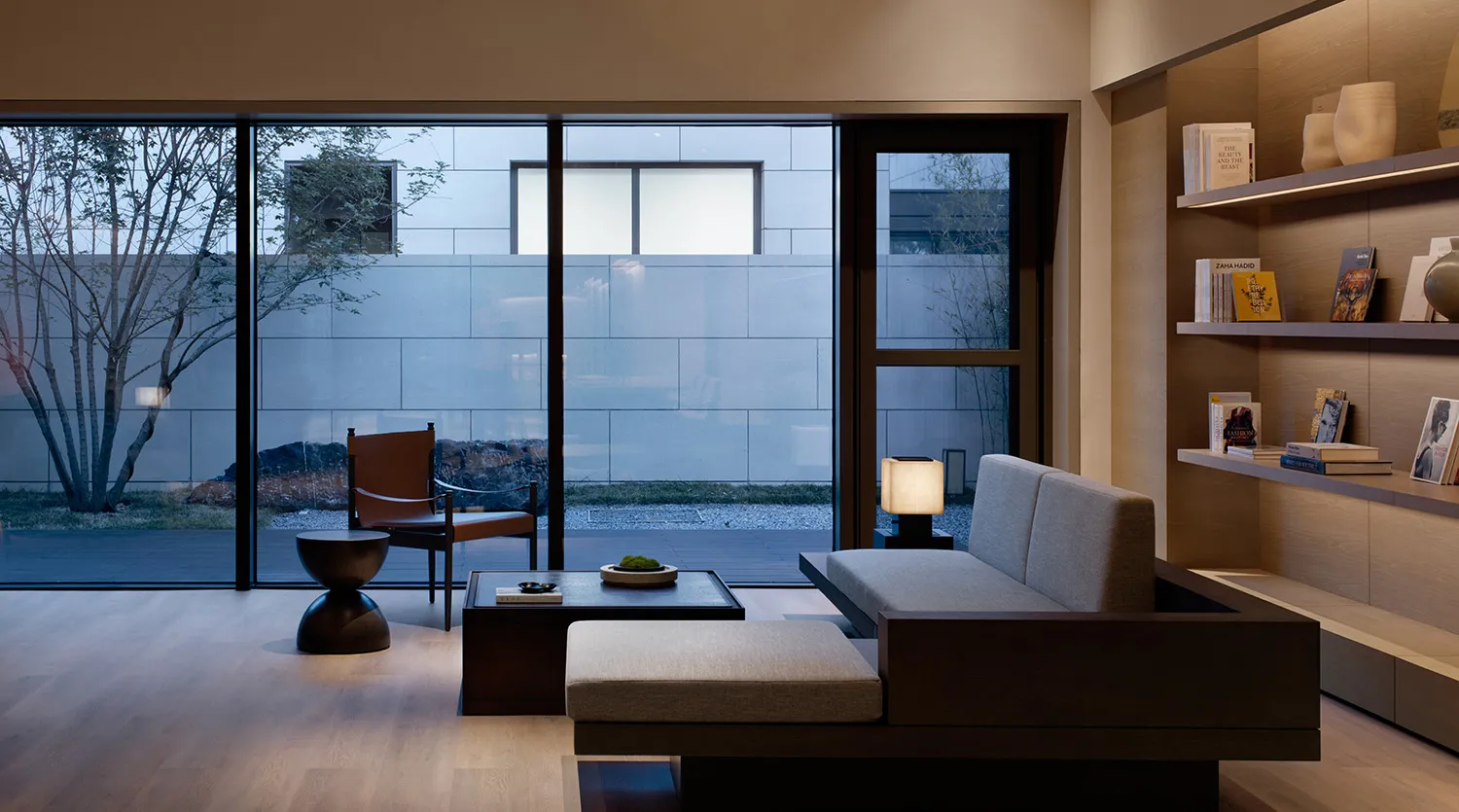A minimalist living room featuring a wooden floor, couch, and side table.