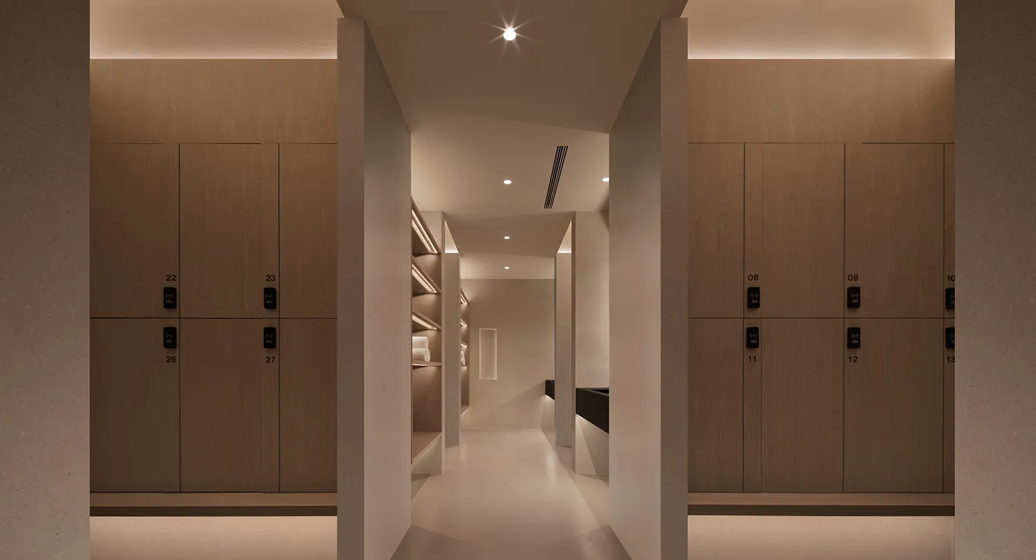 Modern commercial locker room with wooden lockers and white flooring.