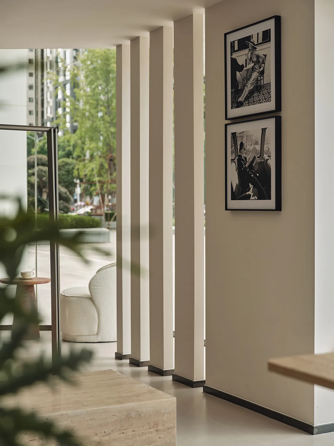 Modern minimalist interior space with white walls, columns, and photographs on the wall.