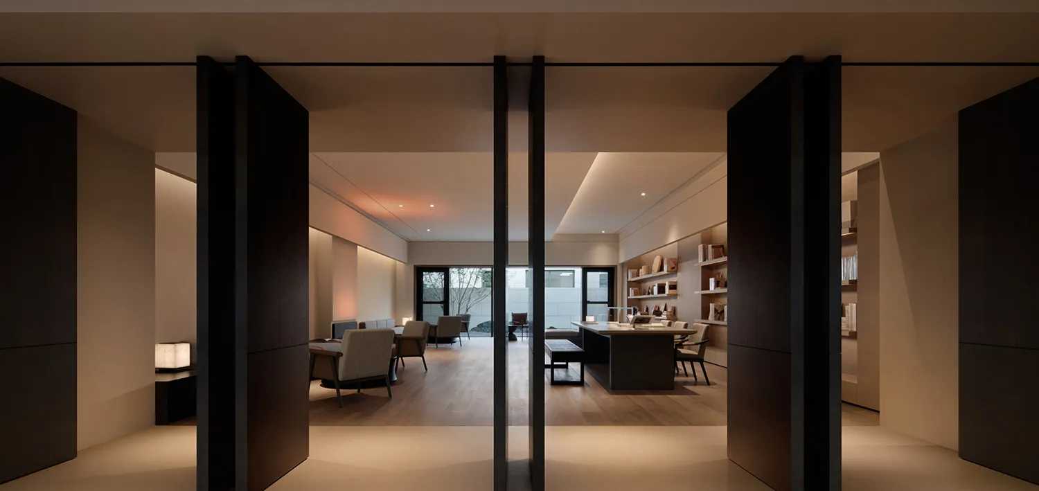 Modern office space with dark wood furnishings, featuring a dark wood desk and chairs, and a large window allowing natural li