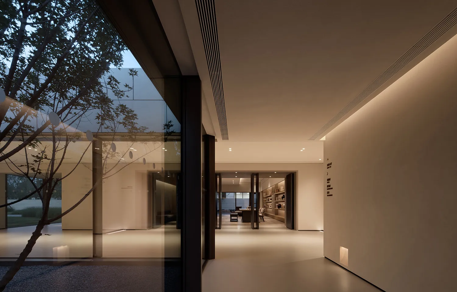 A modern residential hallway with large glass windows, concrete flooring, and laminate accents.