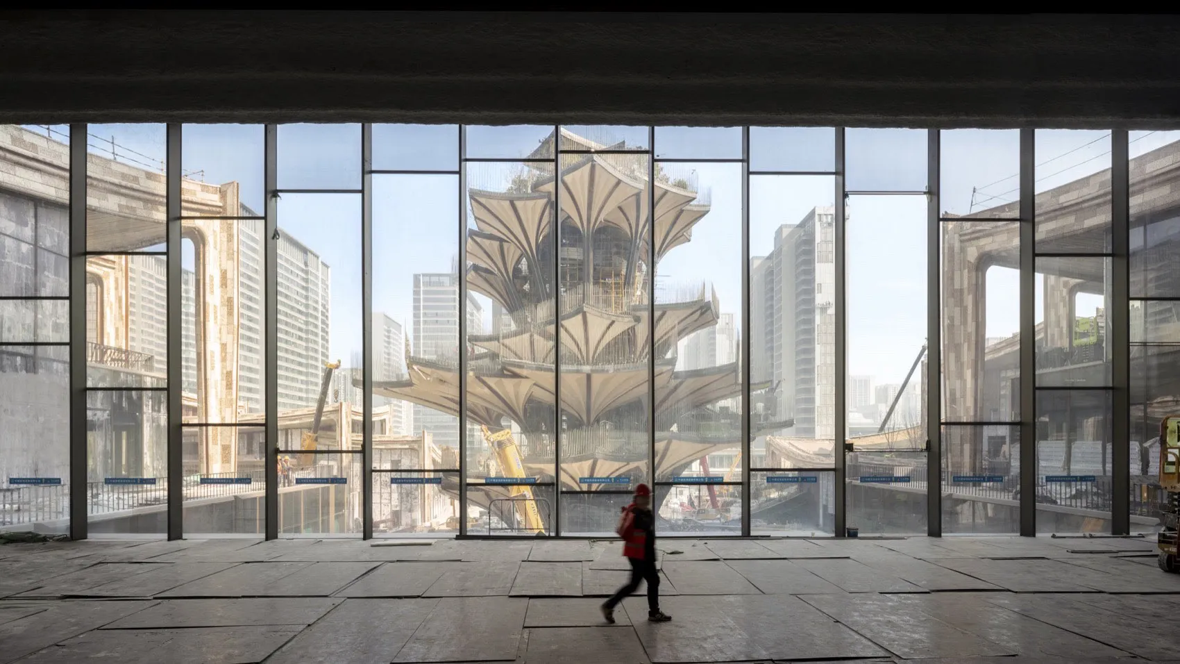 一張照片顯示工地內的大型玻璃窗，反射出周圍的城市景觀，包括一座模
