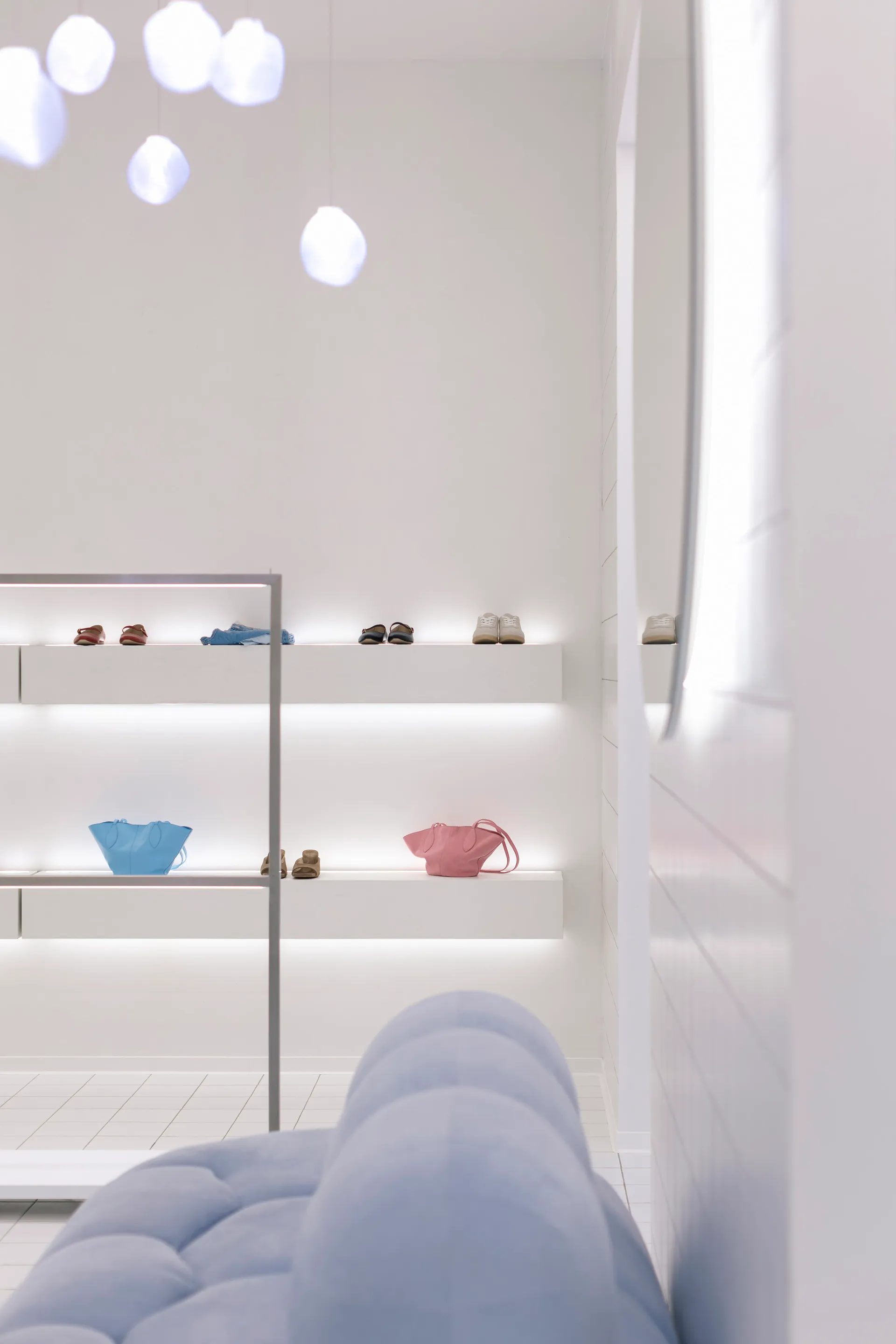 A minimalistic retail space featuring white walls, white shelves, and a white couch.