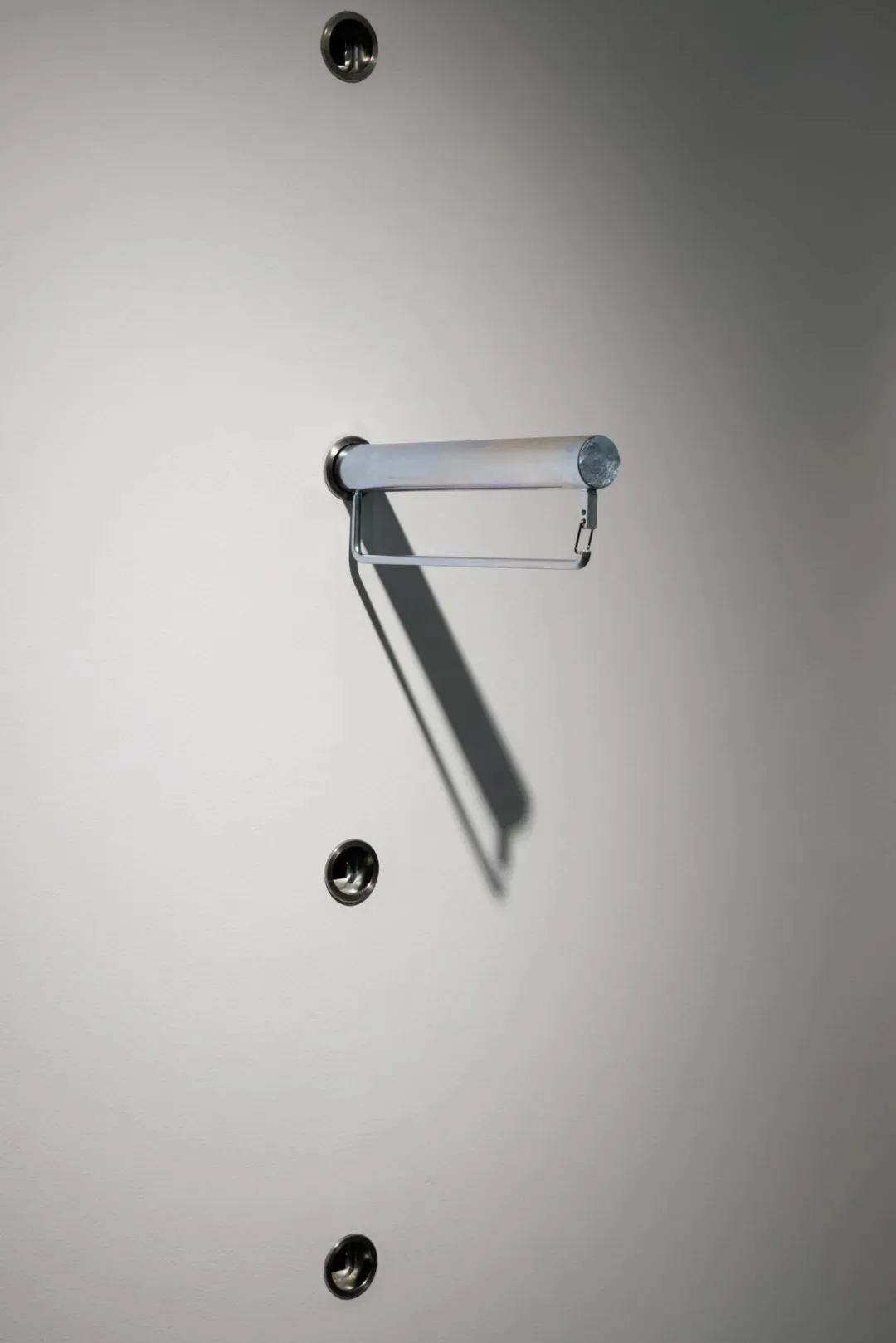 A minimalist metal towel rack mounted on a plain white wall.