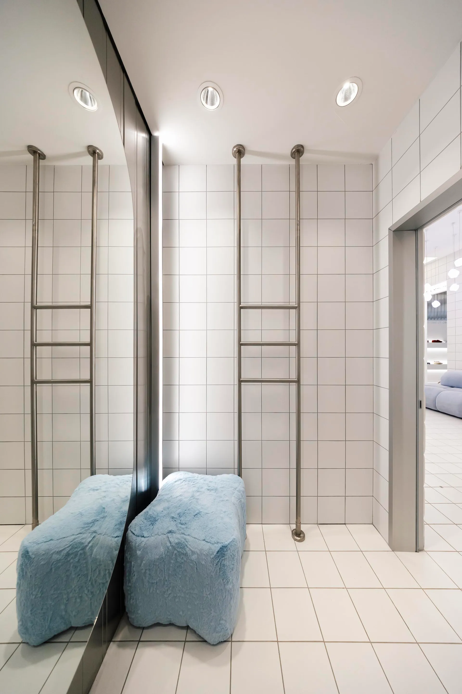 Modern bathroom interior with white ceramic tiles, minimalist design, and industrial-style metal ladders on the wall.