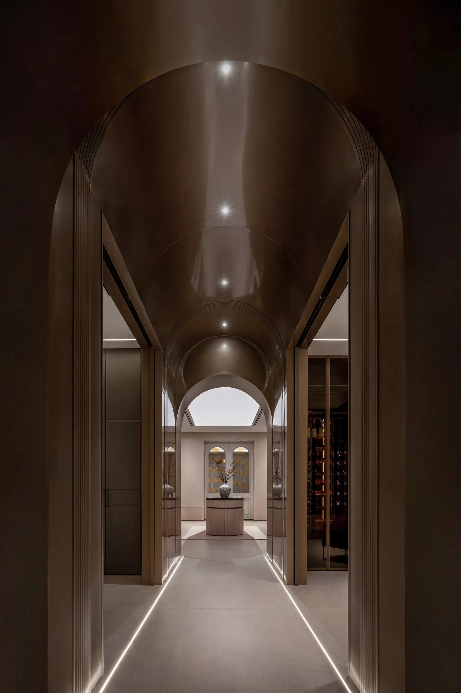 A modern interior featuring a glass and steel corridor with arched ceilings and illuminated pathways.