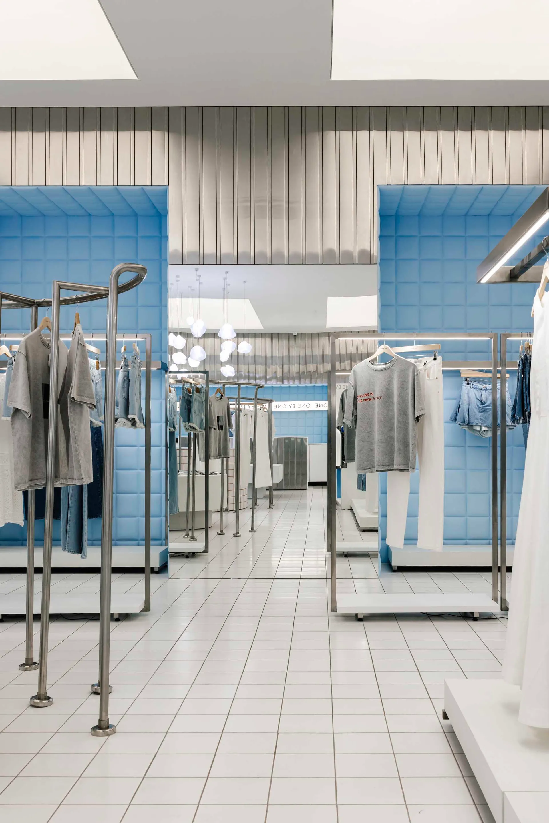 Modern retail store showcasing contemporary interior design with blue-tiled walls and metal fixtures.