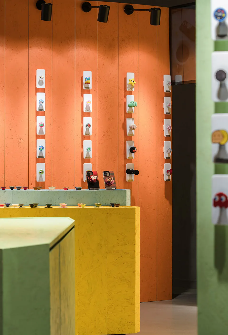 A retail display featuring orange ceramic clay objects on white stands against an orange panel wall.