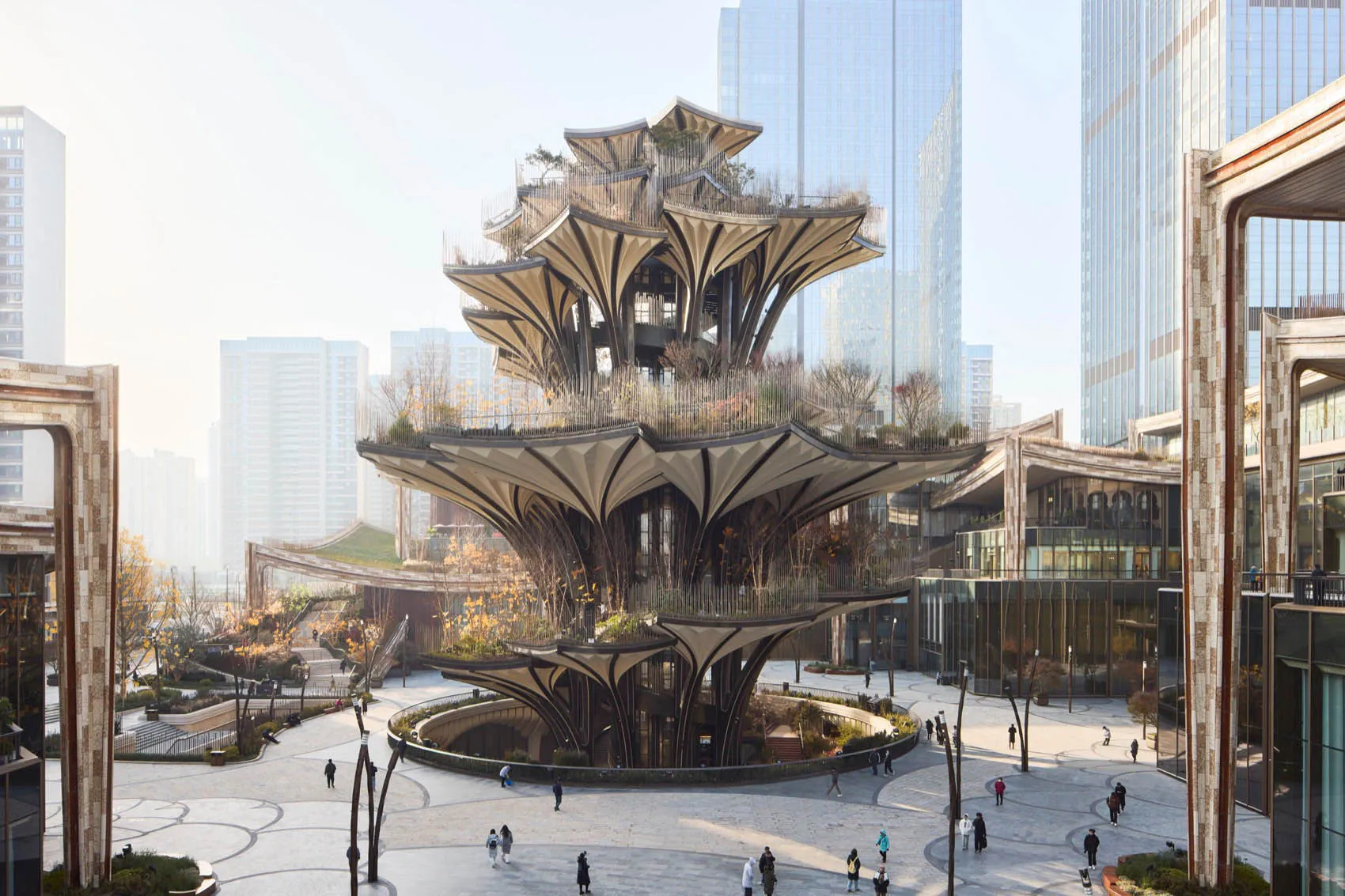A modern public square with a unique, organic-shaped pavilion featuring wood, glass, and concrete materials.