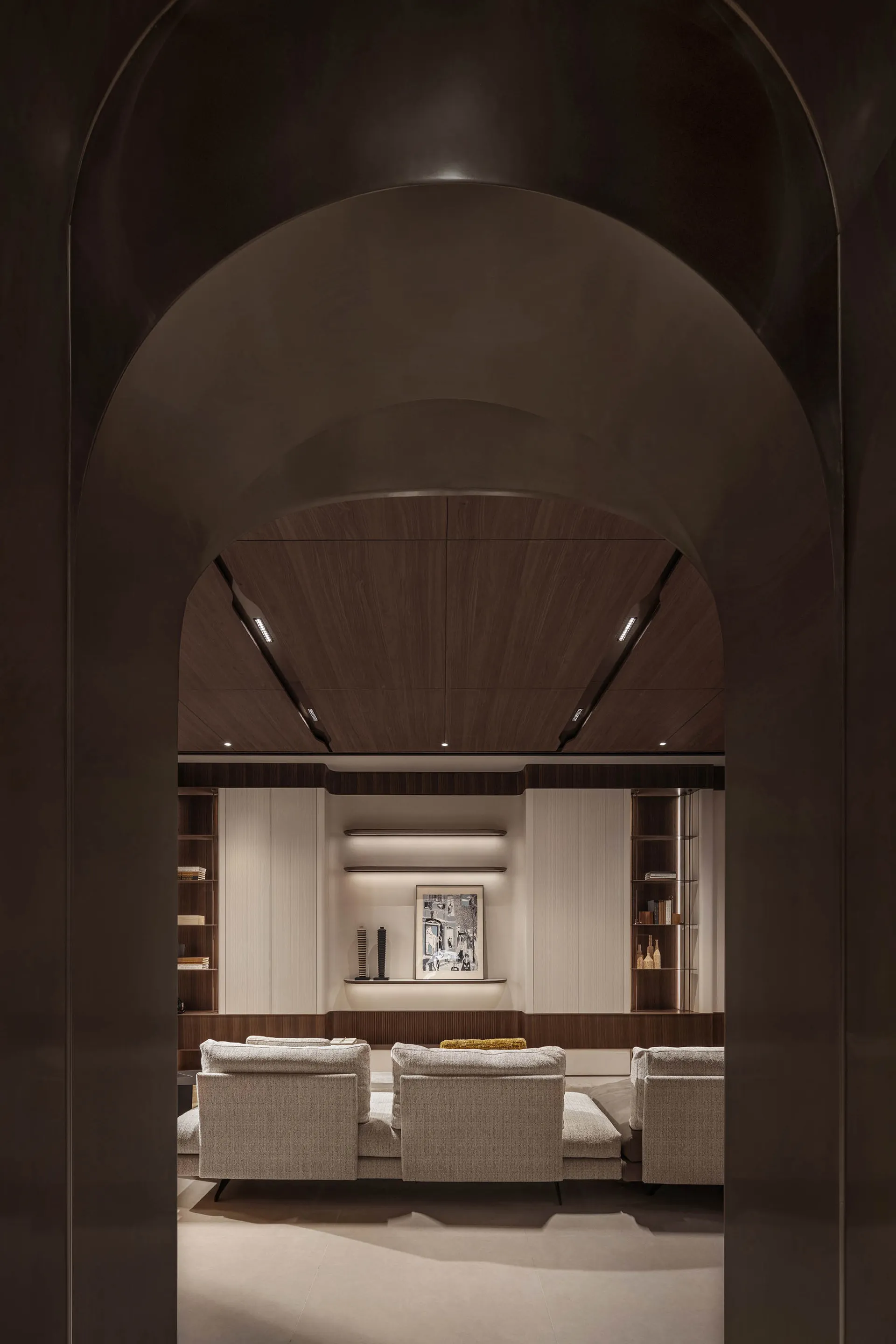 A modern living room featuring wood-paneled walls, upholstered furniture, and minimalist decor.