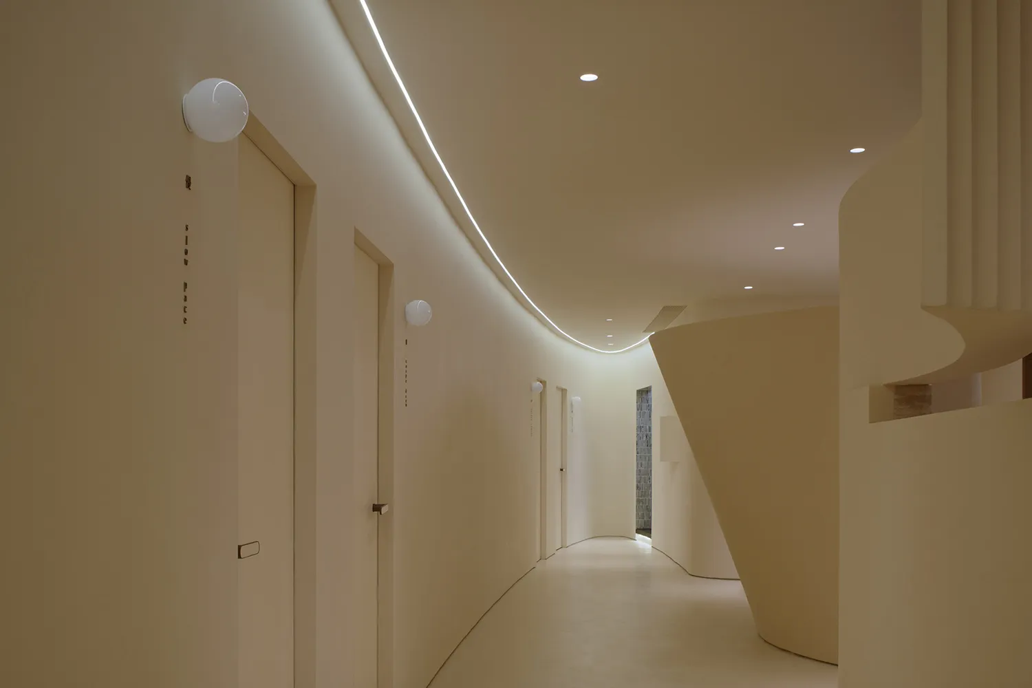 一條現代醫院走廊,牆面採用中性色調,地板光滑平整,並有曲線建築元素。