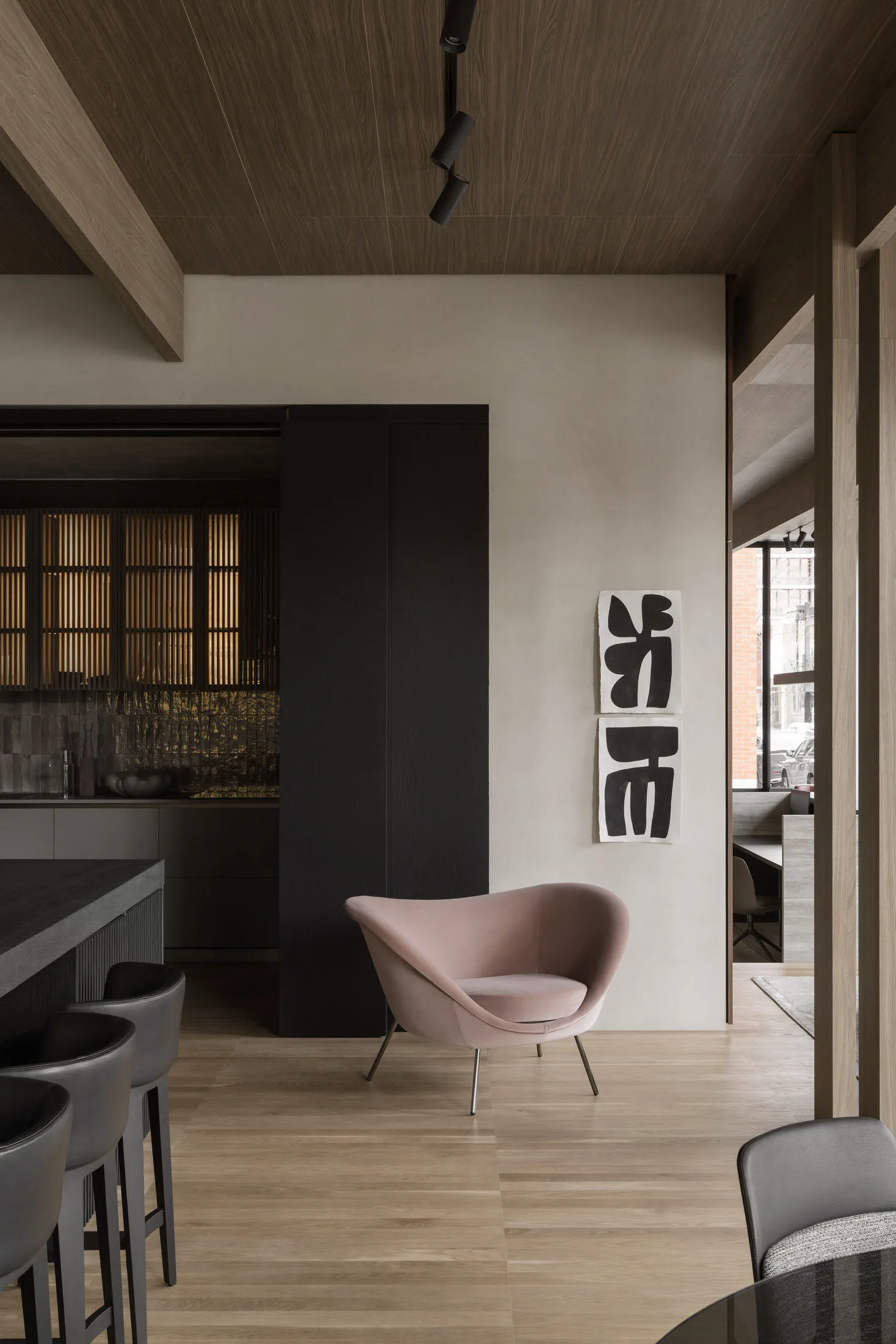 Modern living room featuring minimalist decor with wooden furniture and a pink armchair.
