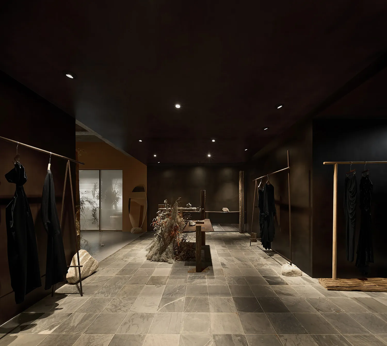 一間現代都會服飾店,採用石材地板與混凝土牆面,呈現極簡設計與工業風照明。