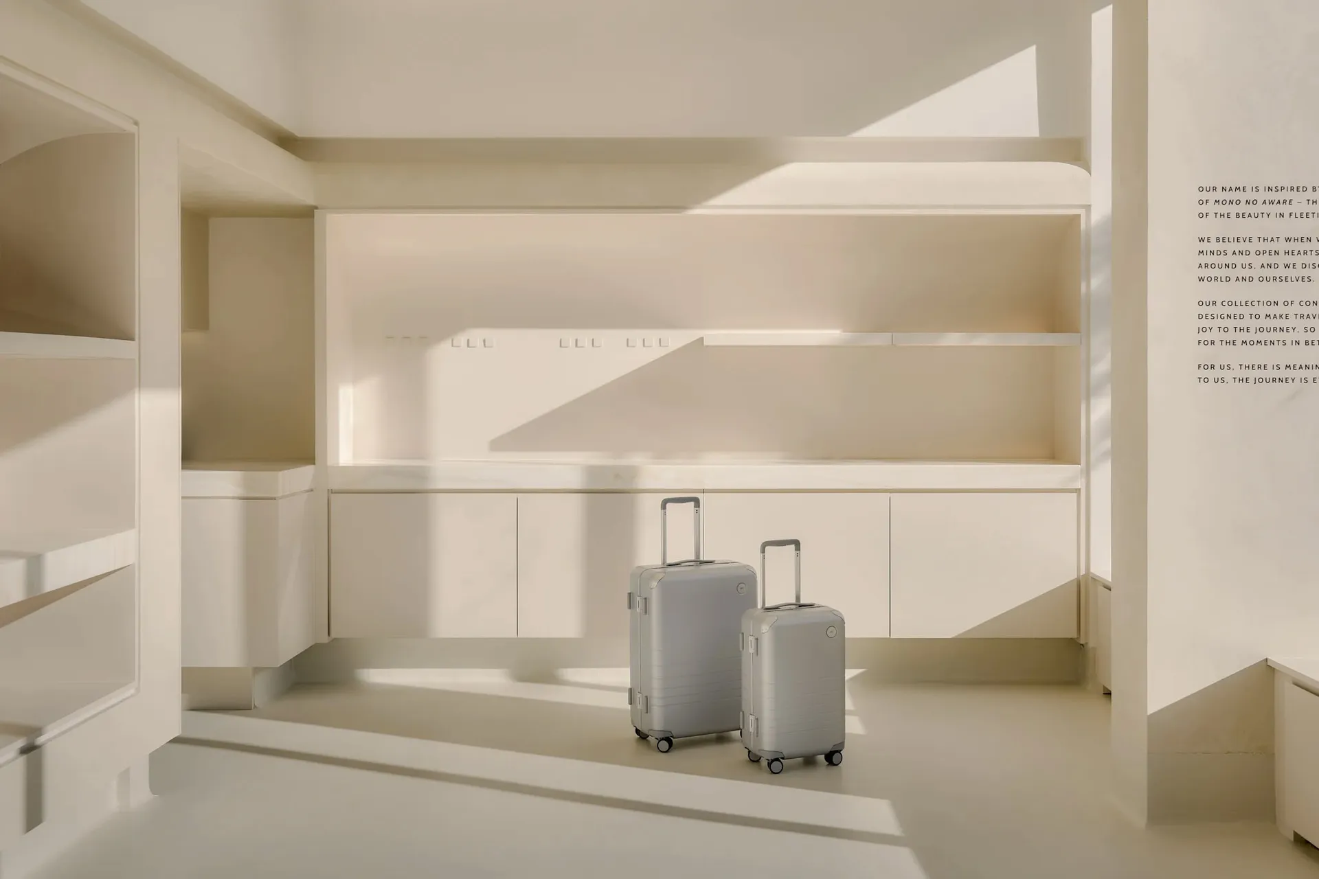 A minimalistic, white interior with two metallic suitcases on wheels.