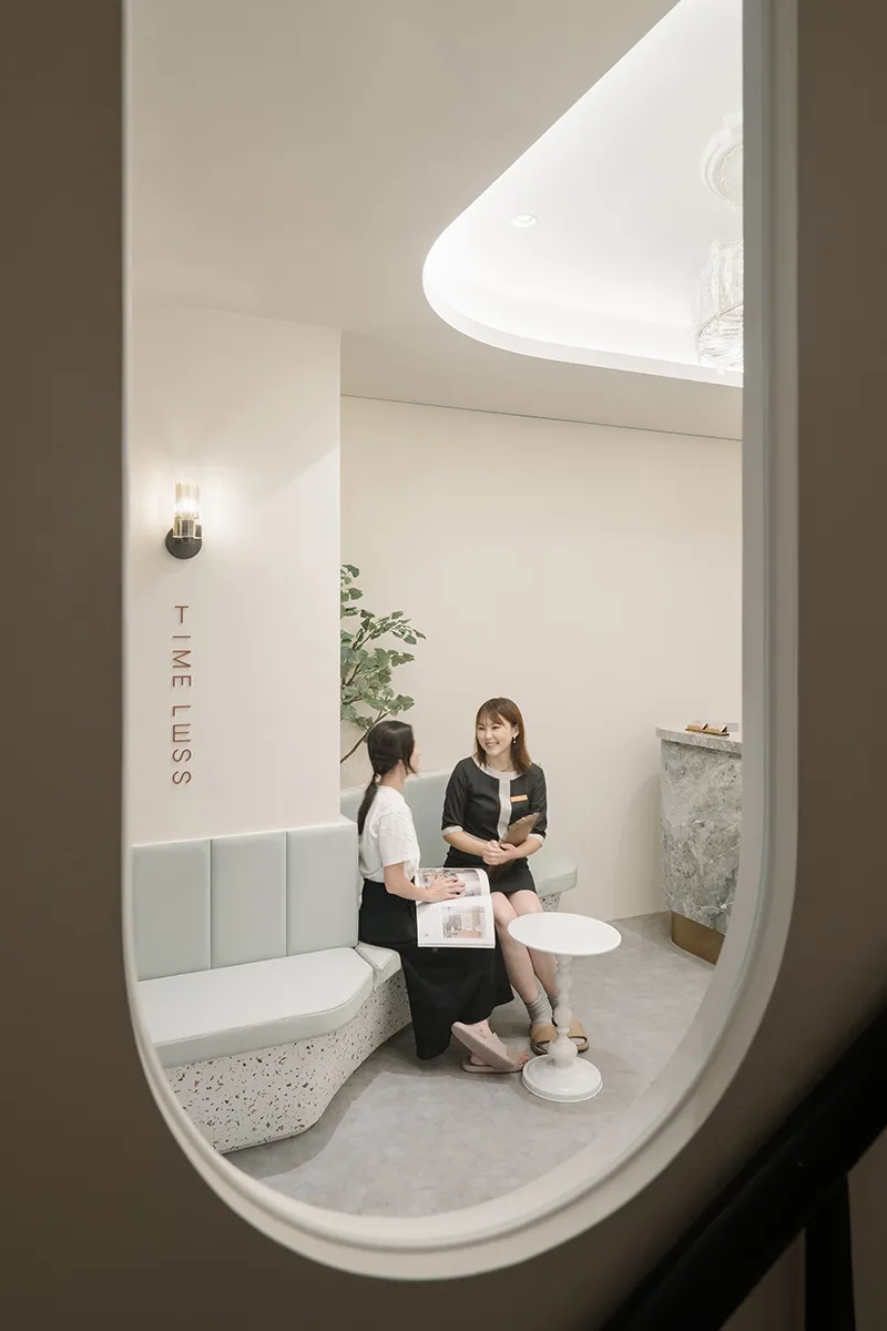 Two women in a modern spa reception area with a sleek, minimalist interior.