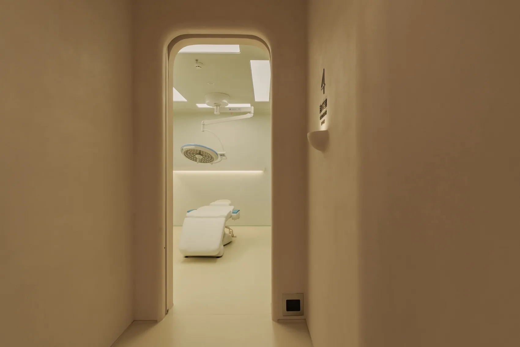 A minimalist hospital room with white furniture and a white ceiling.