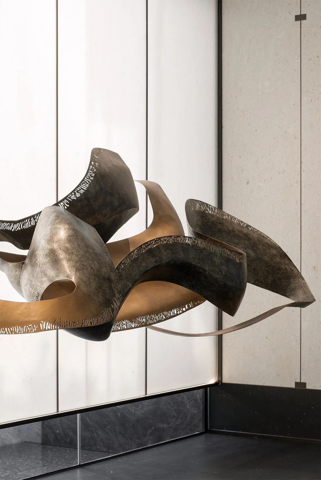 An abstract metallic sculpture with smooth, undulating forms.