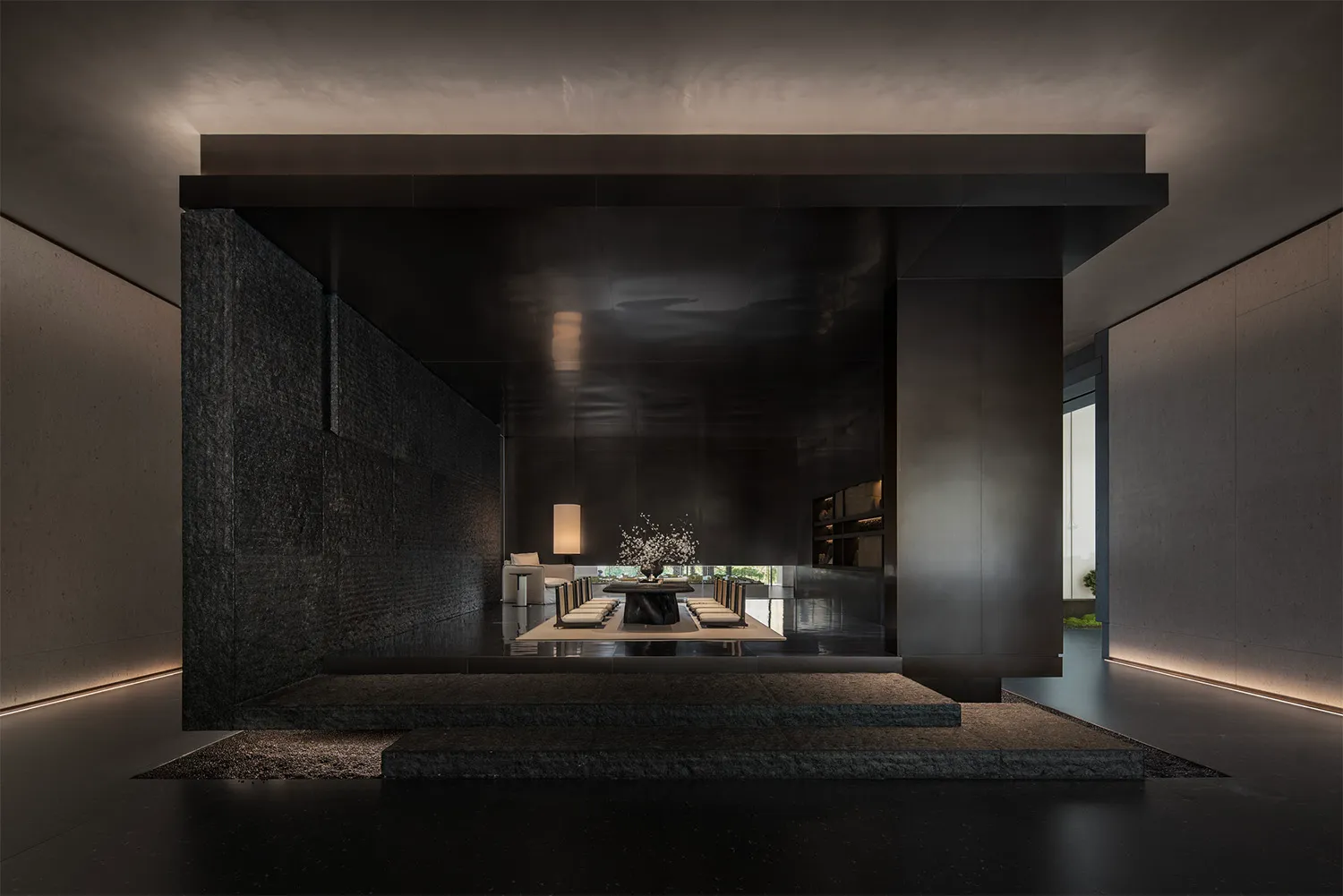 A modern minimalist living room with concrete walls and a central lighting feature.