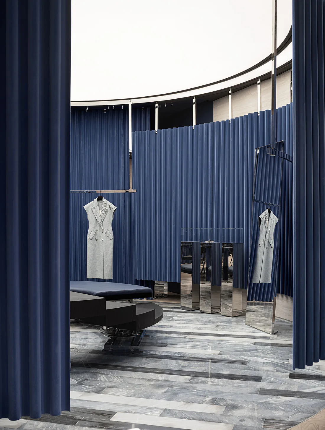 Modern retail storefront featuring blue curtains, marble floors, wood-paneled walls, transparent mirrors, and a white ceiling
