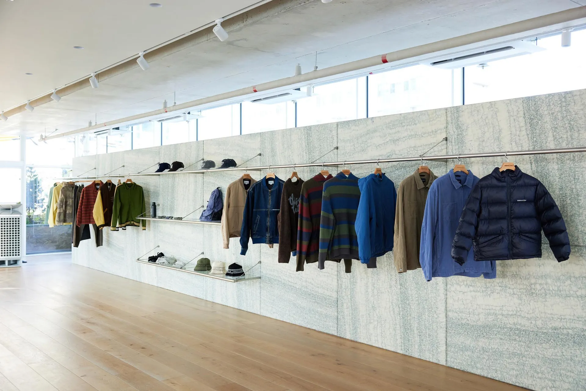 店內服裝展示,架上與衣架陳列多款外套與配件。