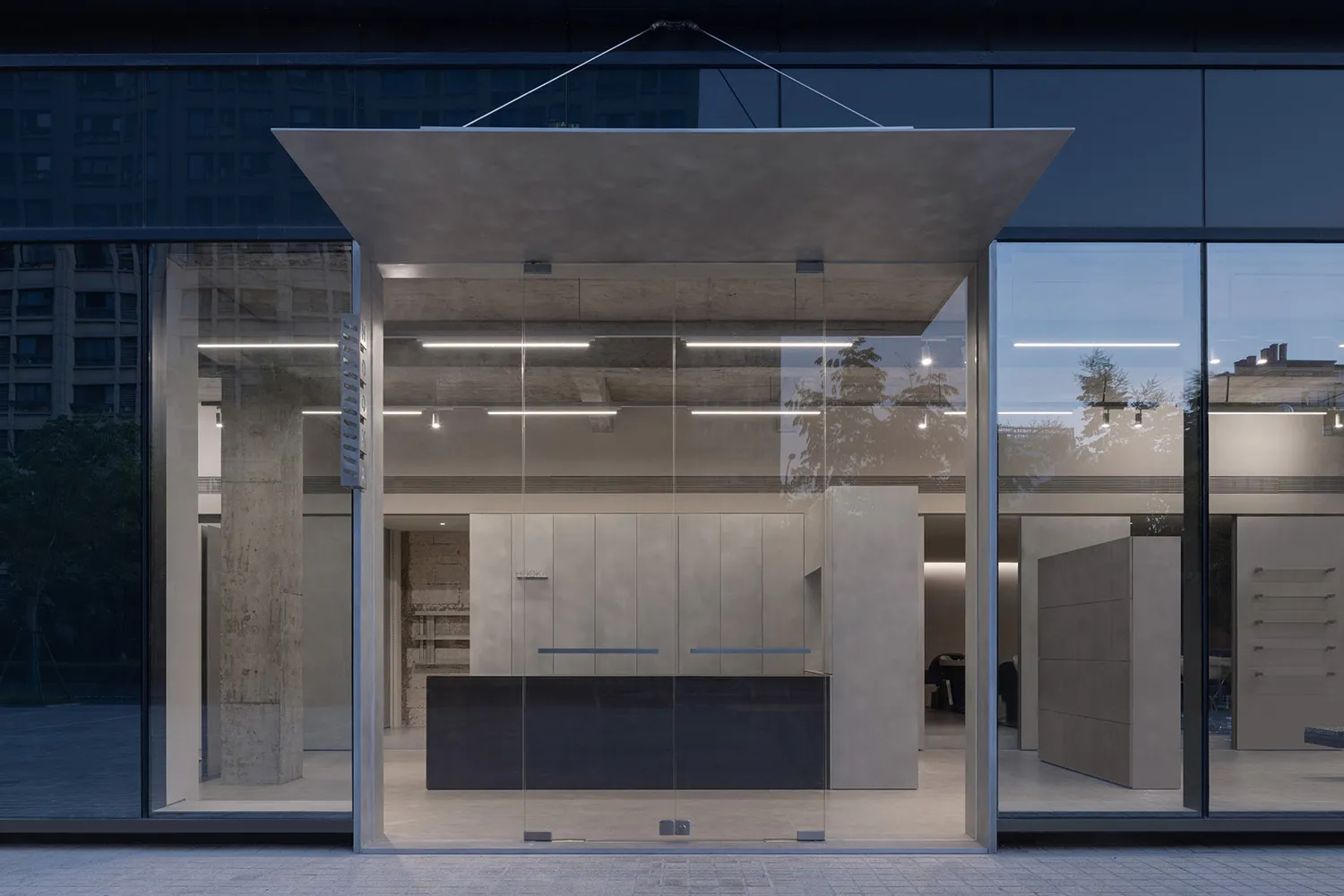 A minimalist storefront with large glass windows and concrete elements.