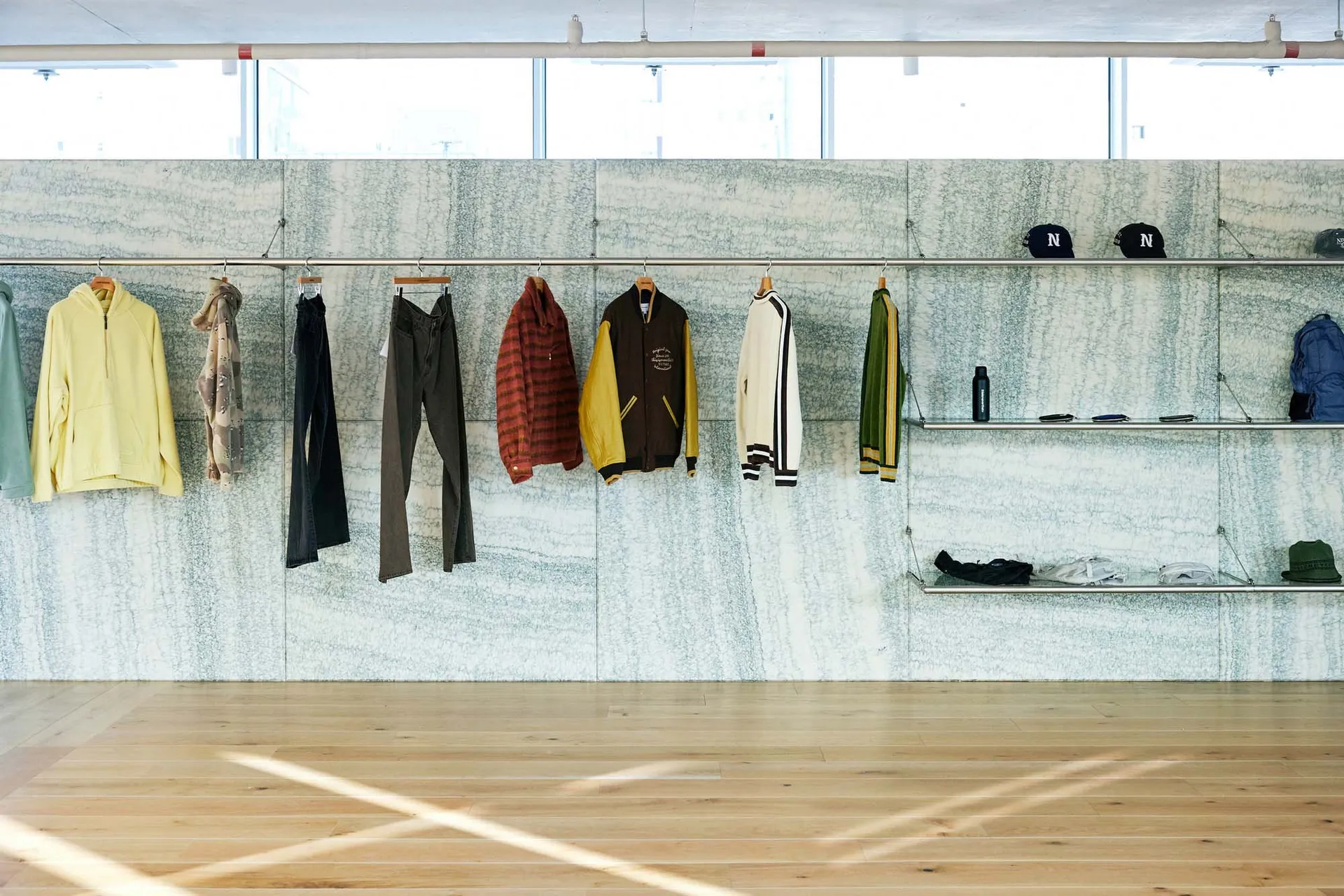 A modern clothing shop featuring marble walls with racks of hanging garments and shelves.