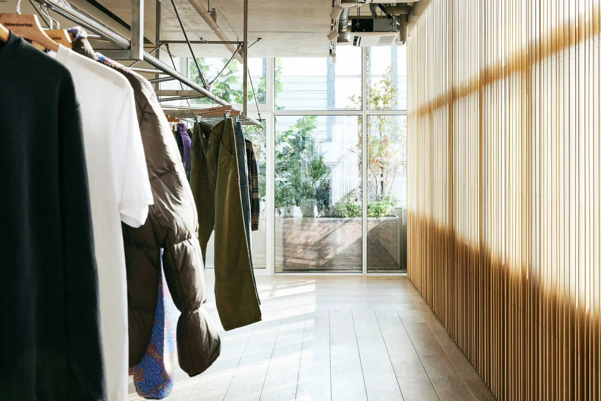 Modern retail store interior with wooden walls and clothing racks.