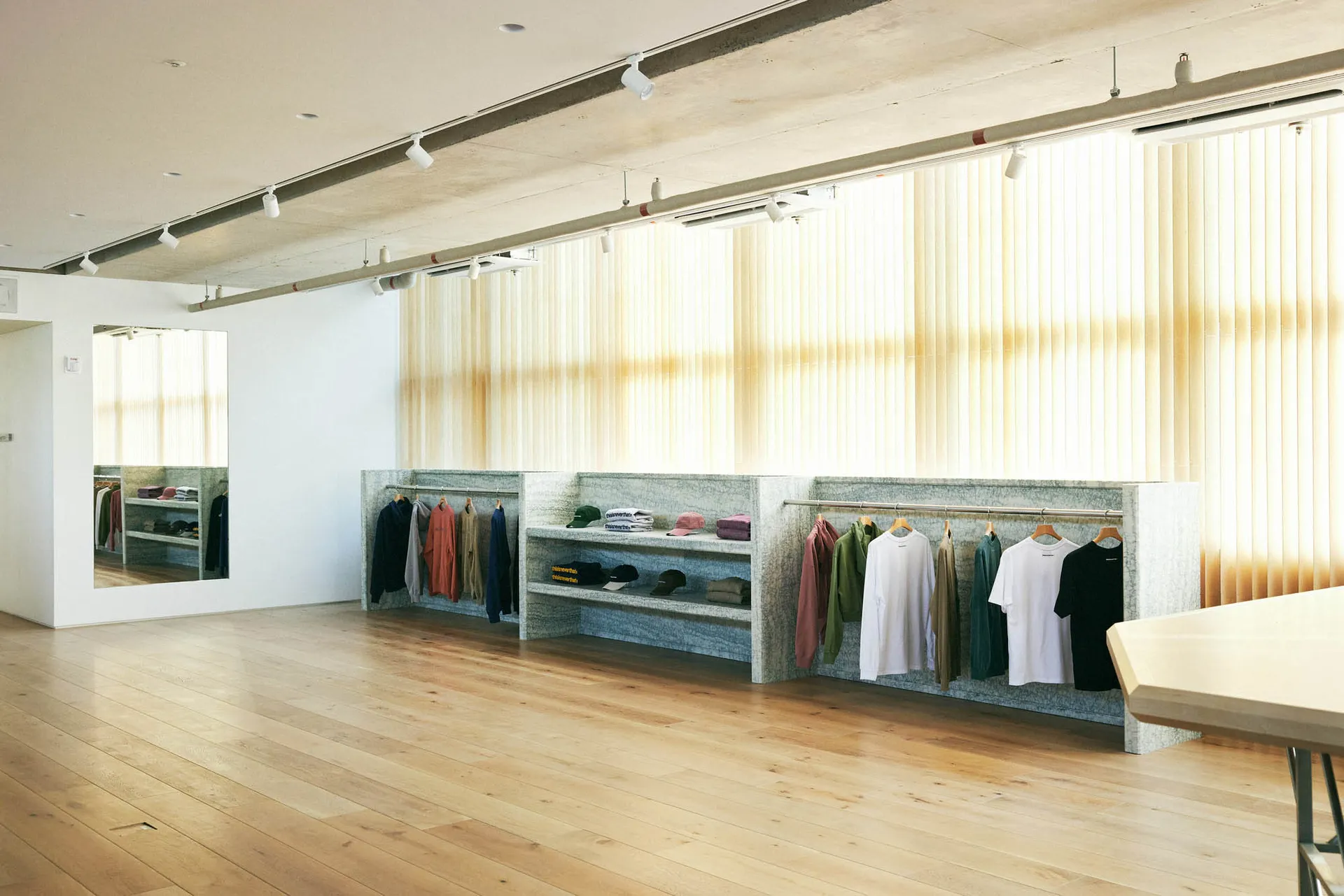 A modern retail space featuring a concrete shelf with various clothing items hanging on it.