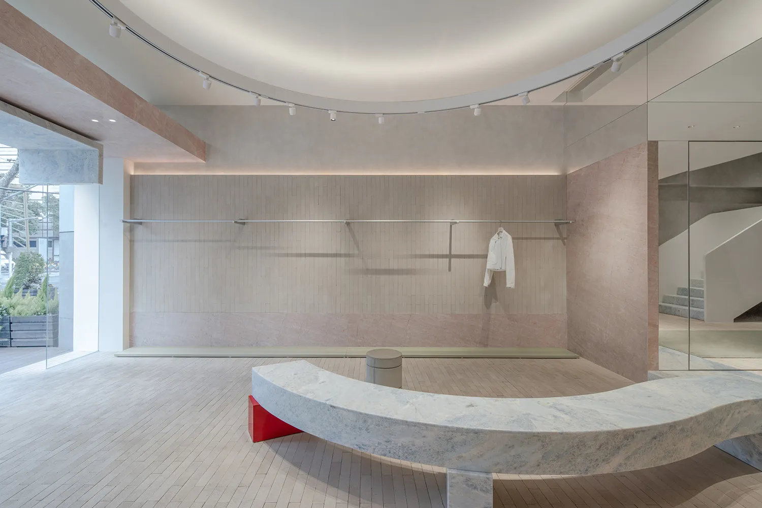 A minimalistic retail space featuring white walls, concrete flooring, and a sleek, curved seating area in a contemporary desi