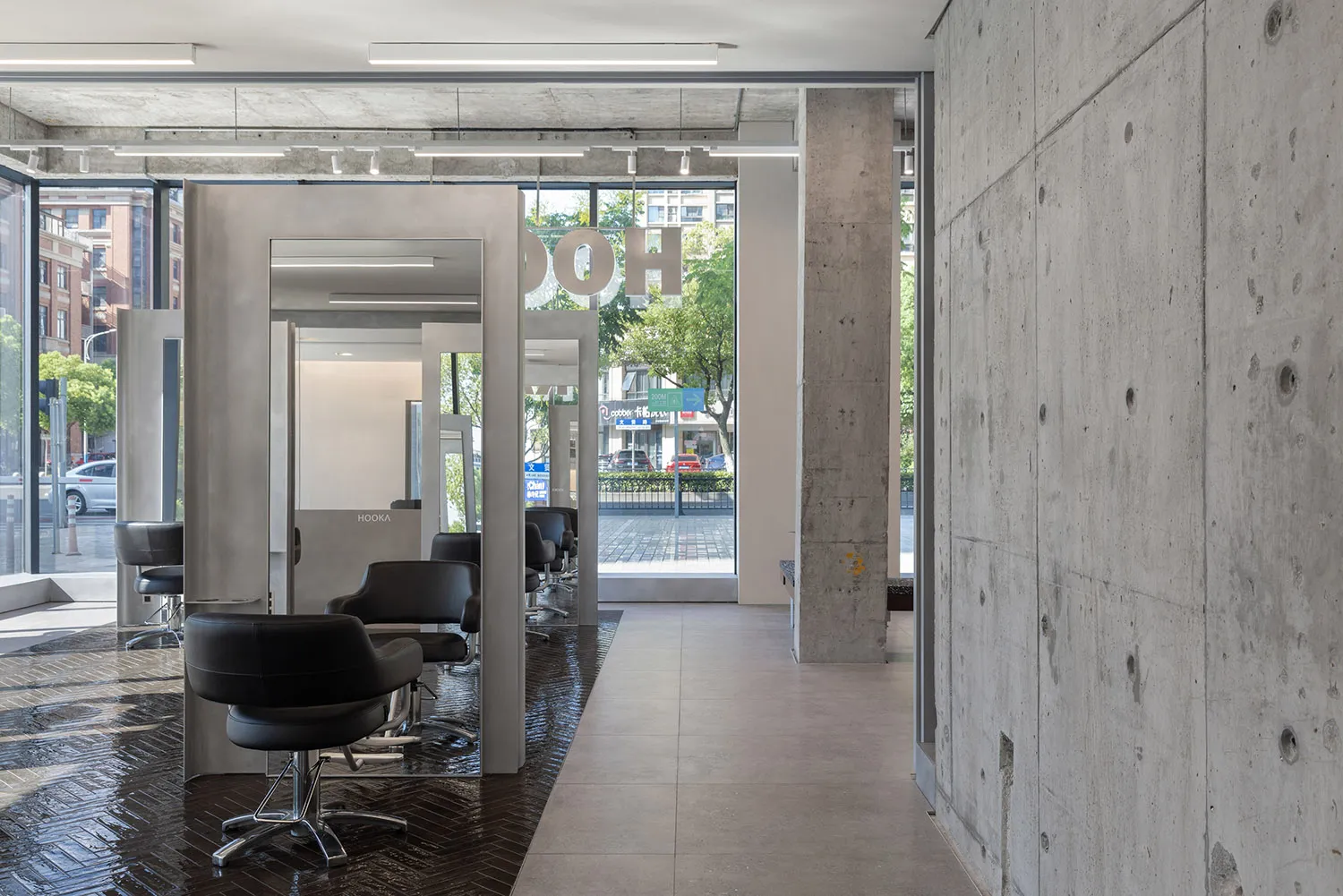 Modern salon interior with black chairs, concrete walls, and glass elements.