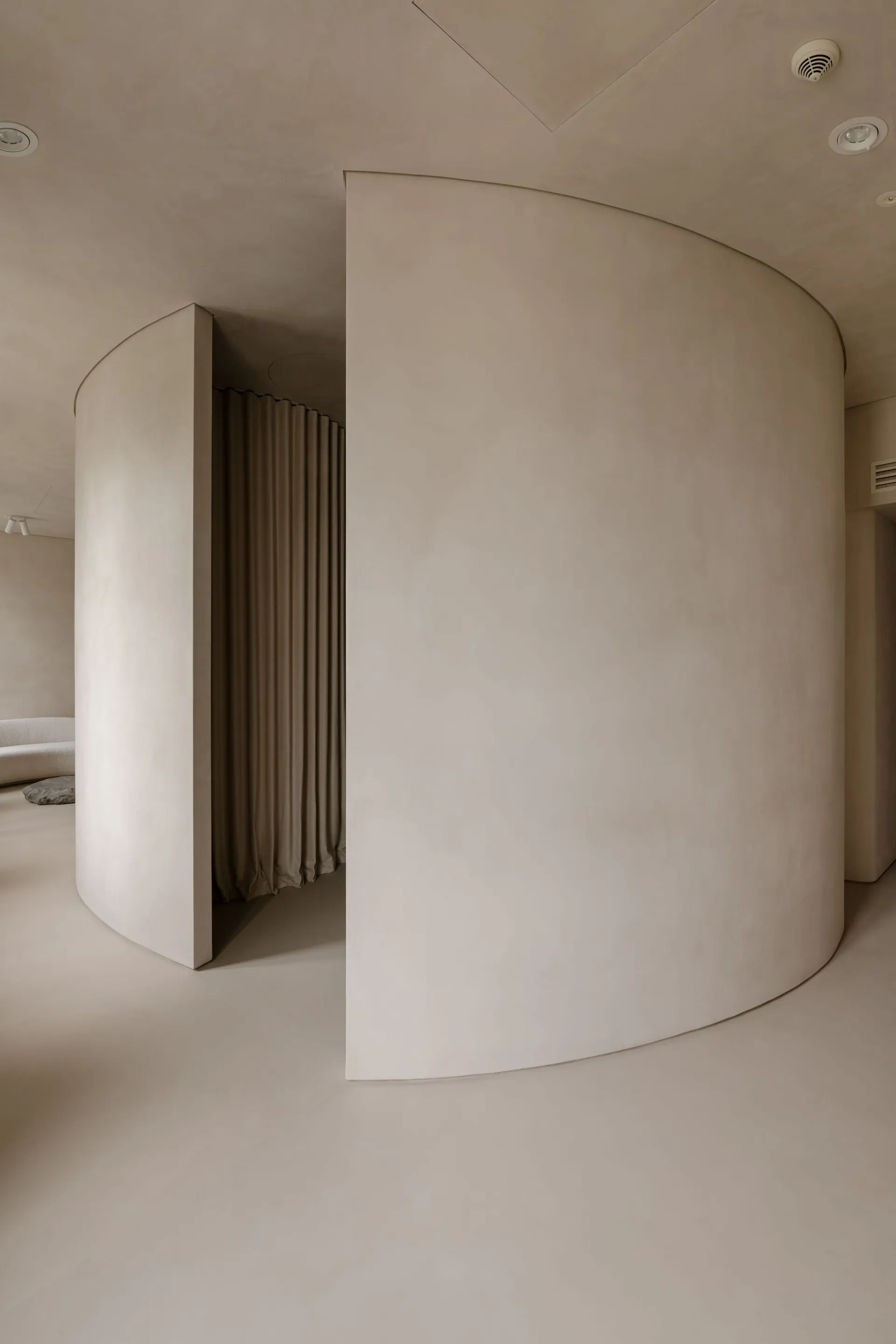 A minimalist space with smooth, curved concrete walls and a neutral color palette.