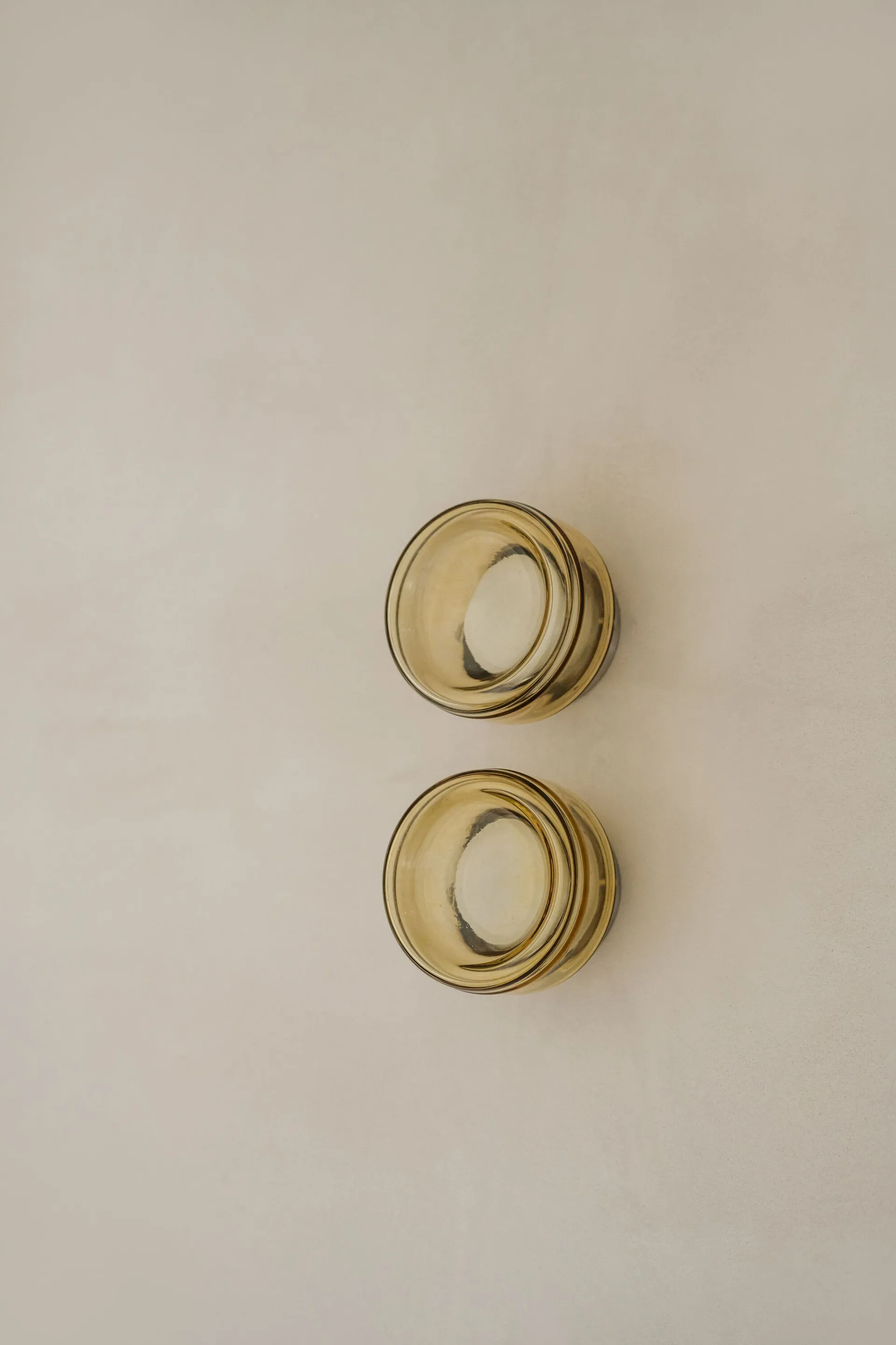 Two modern, amber-colored glass bowls on a neutral background.