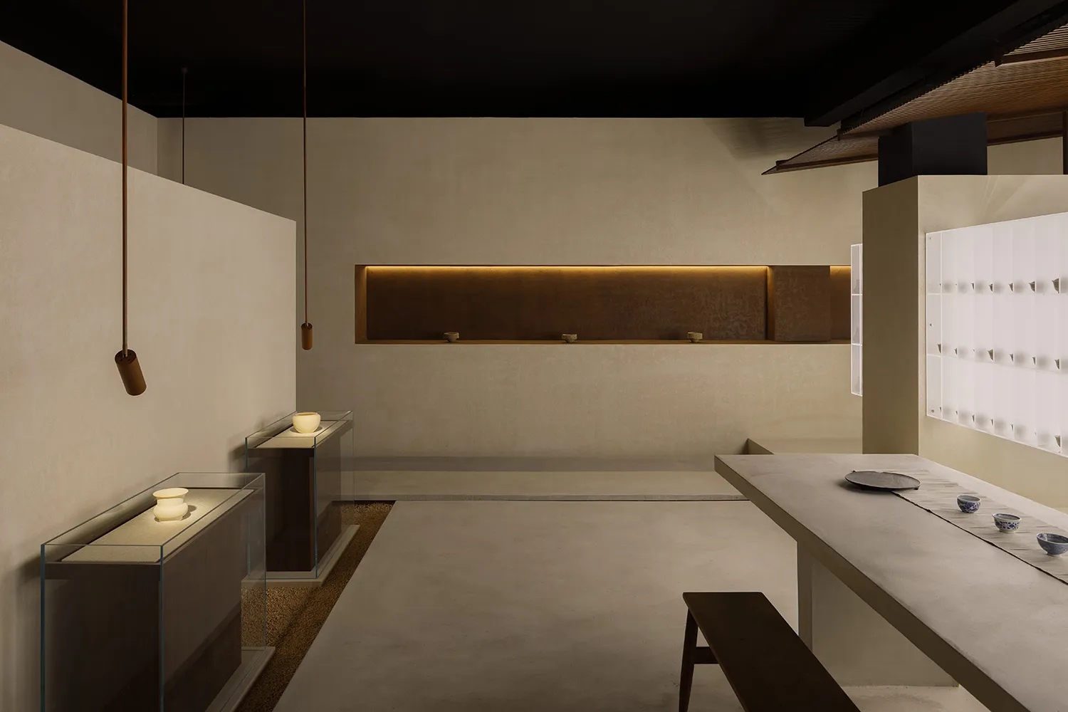 Clean, minimalist restaurant interior with concrete walls and countertops, illuminated by soft, ambient lighting.