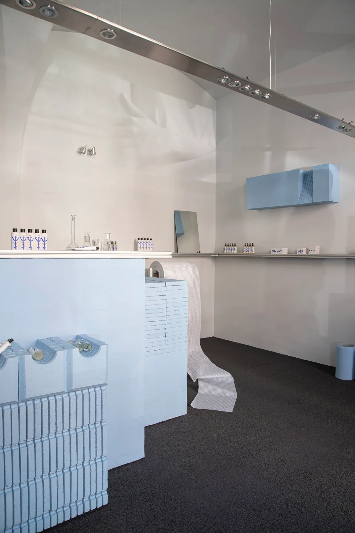 Modern storefront with blue accents, featuring concrete, glass, and metallic elements.