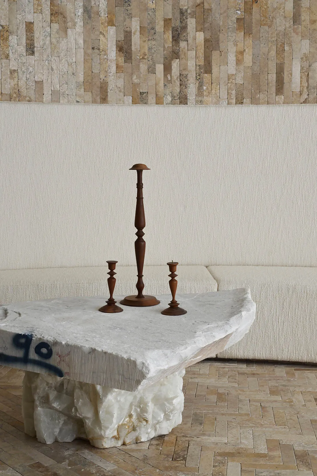A modern marble coffee table with three wooden candle holders in a living room setting.