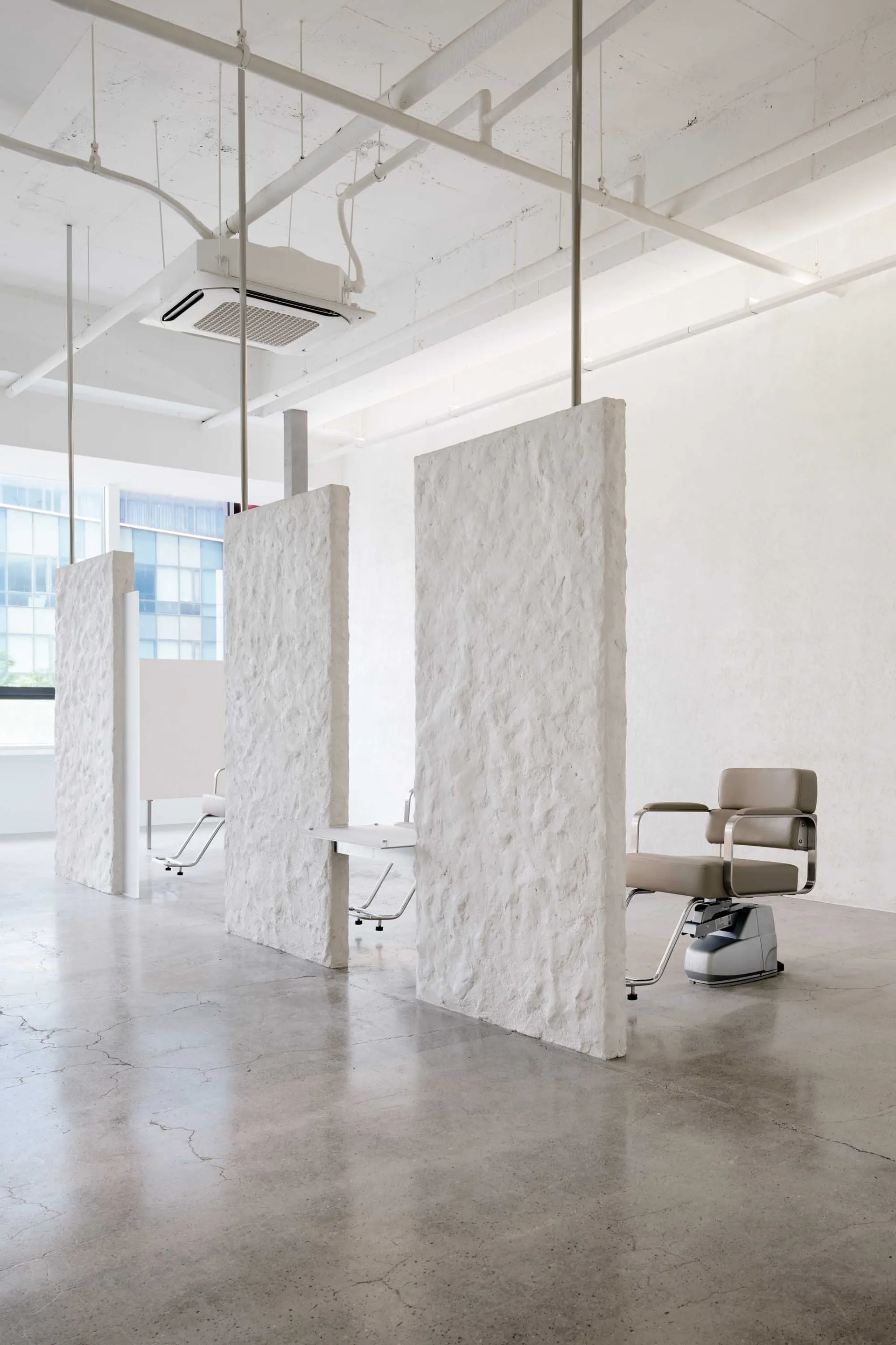 Minimalist commercial interior with concrete walls and floors, featuring modern furniture.