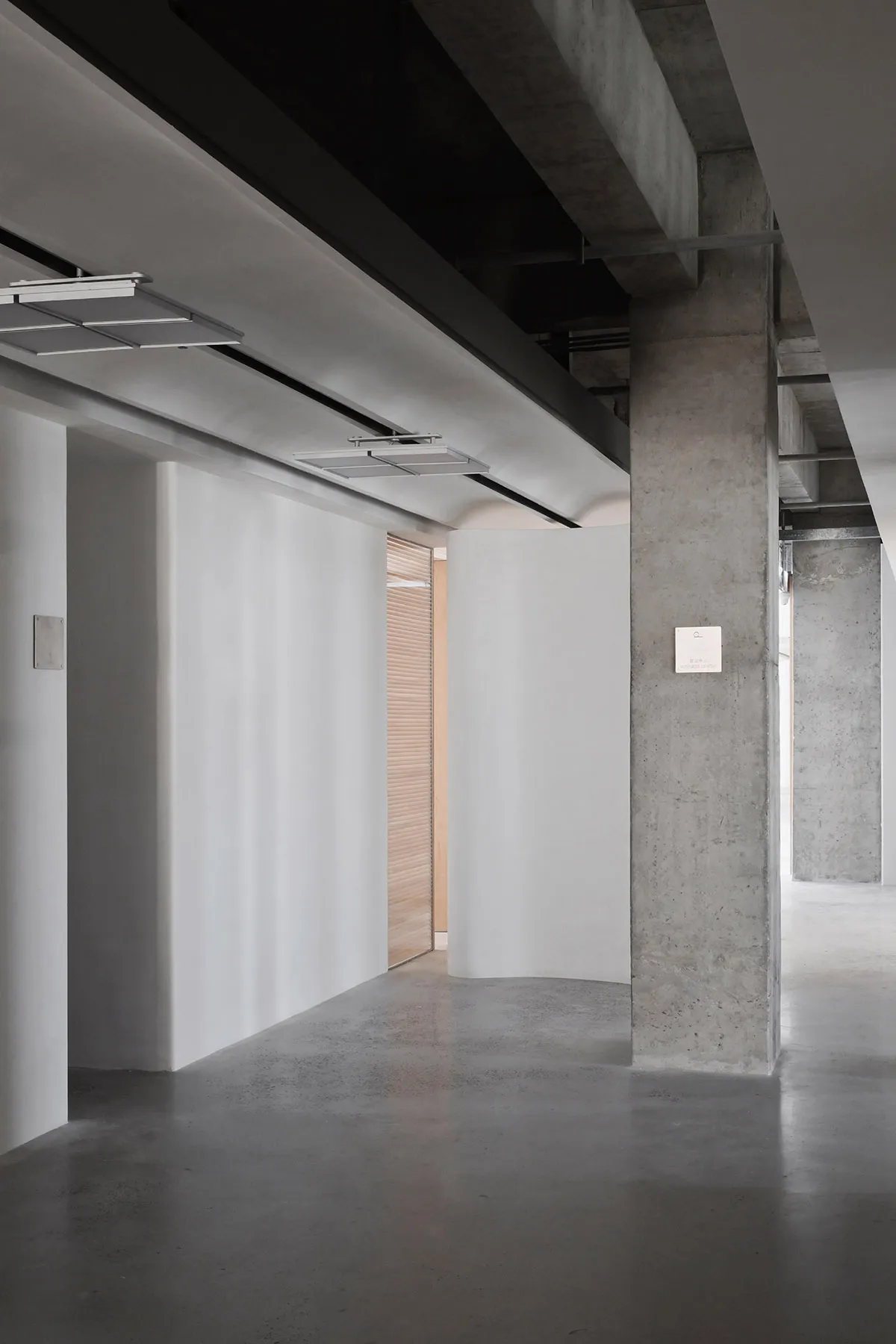 A sleek, minimalist office lobby with concrete walls and a concrete floor.