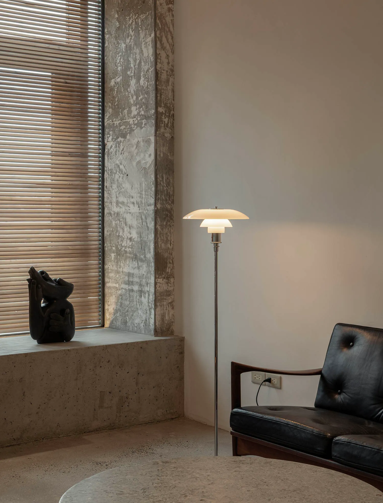 Minimalist living room featuring concrete walls, a concrete floor, and a minimalist floor lamp.
