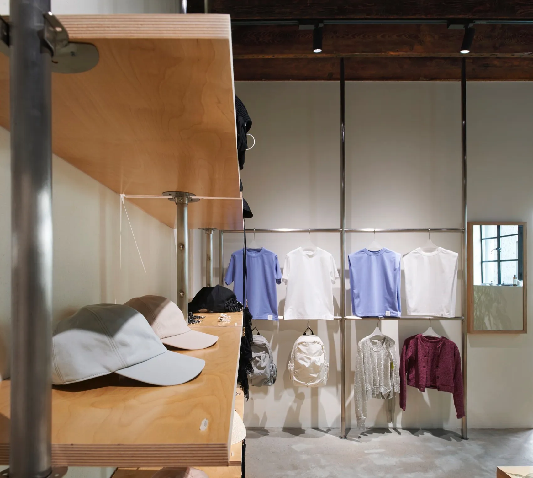 A modern retail store with metallic shelves displaying various clothing items and accessories.