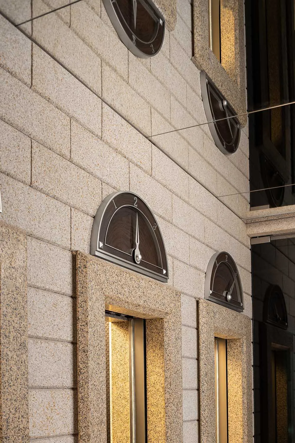 A close-up of a granite exterior building facade with glass doors.