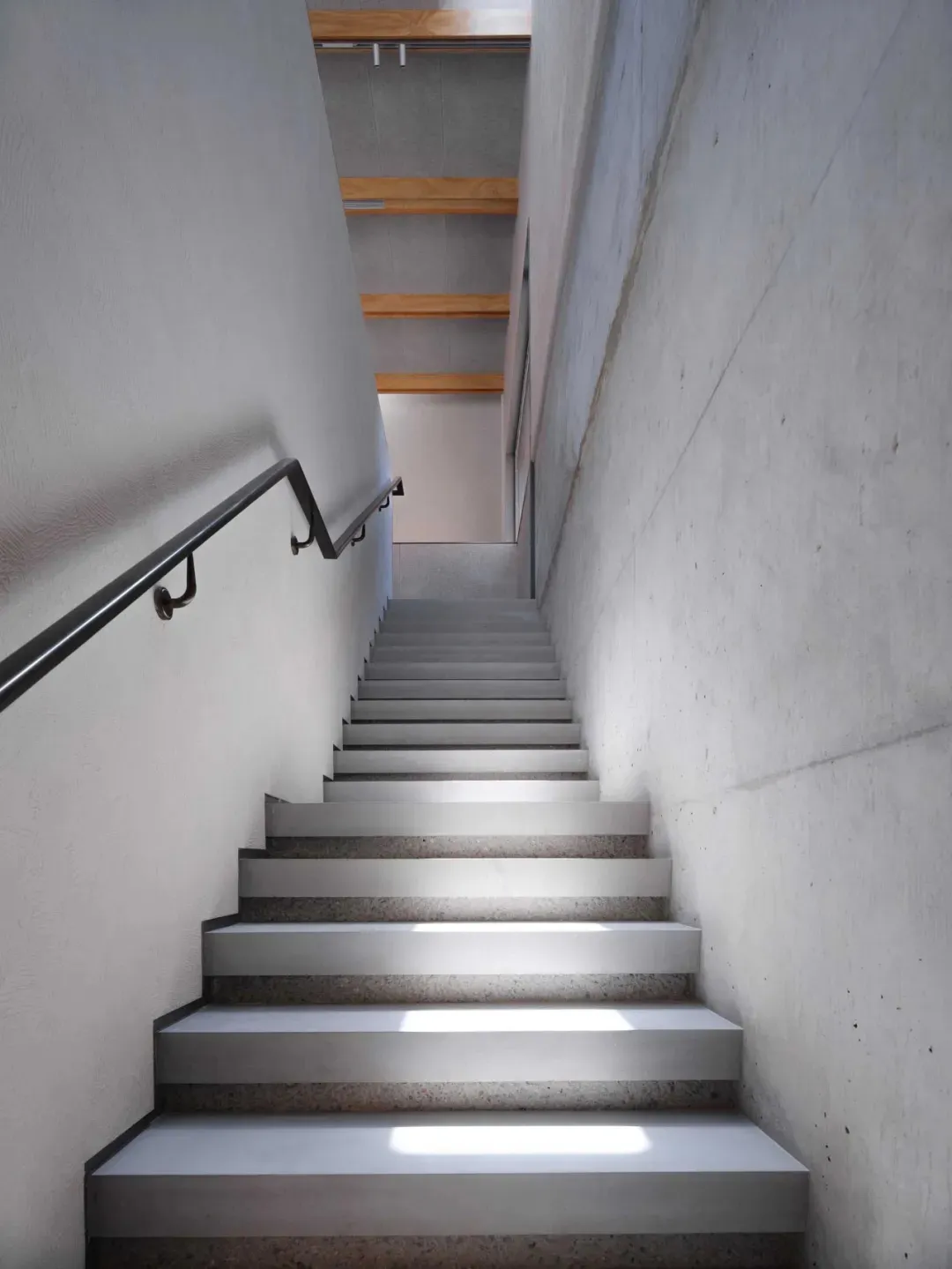 Modern staircase featuring smooth concrete steps and integrated steel railings.