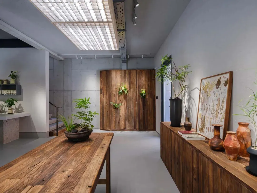 工業風零售空間，展示木質桌台與混凝土牆面，搭配植物與花瓶。