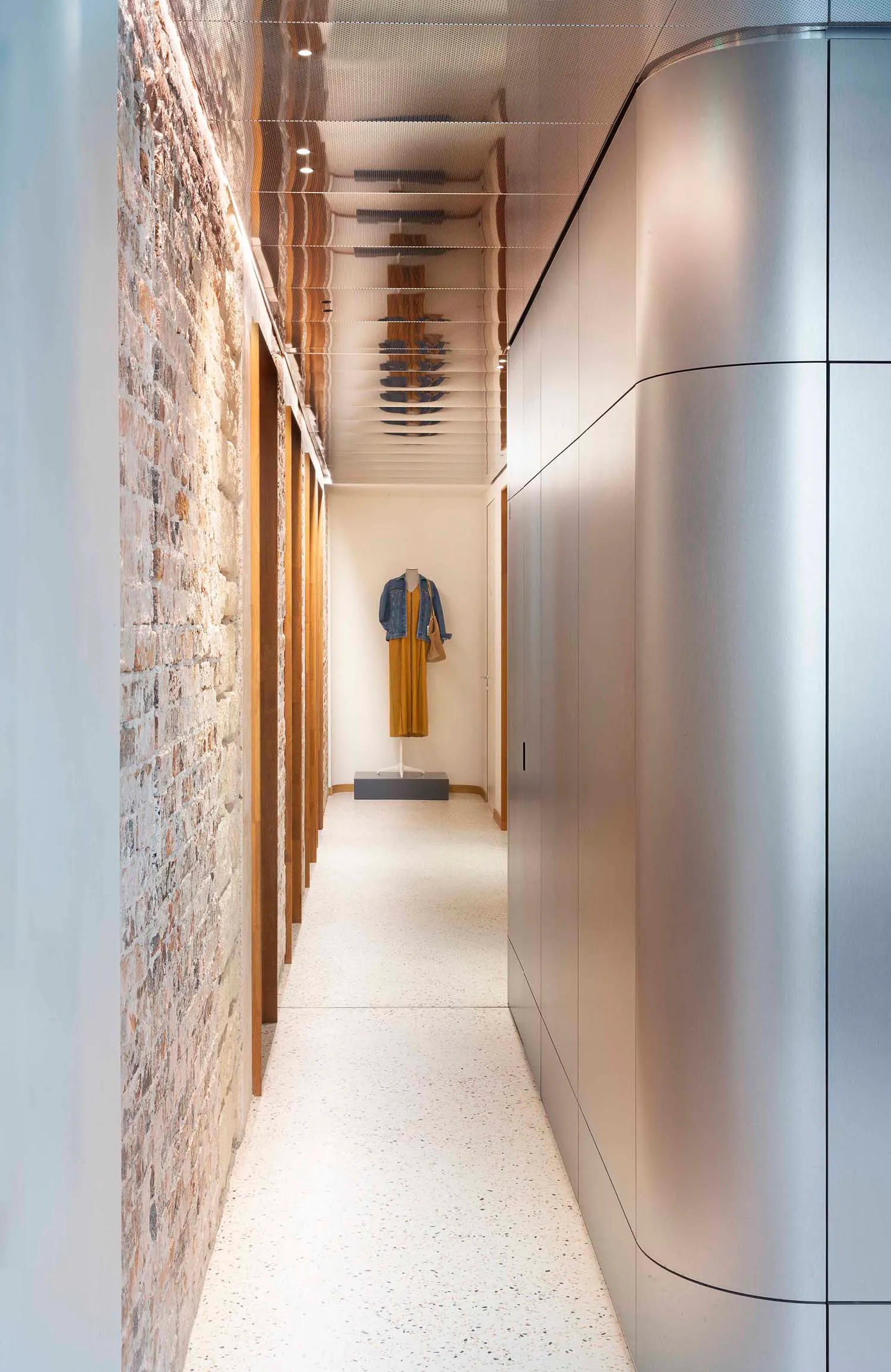 A modern interior corridor made of aluminum with a minimalist design and white speckled flooring.